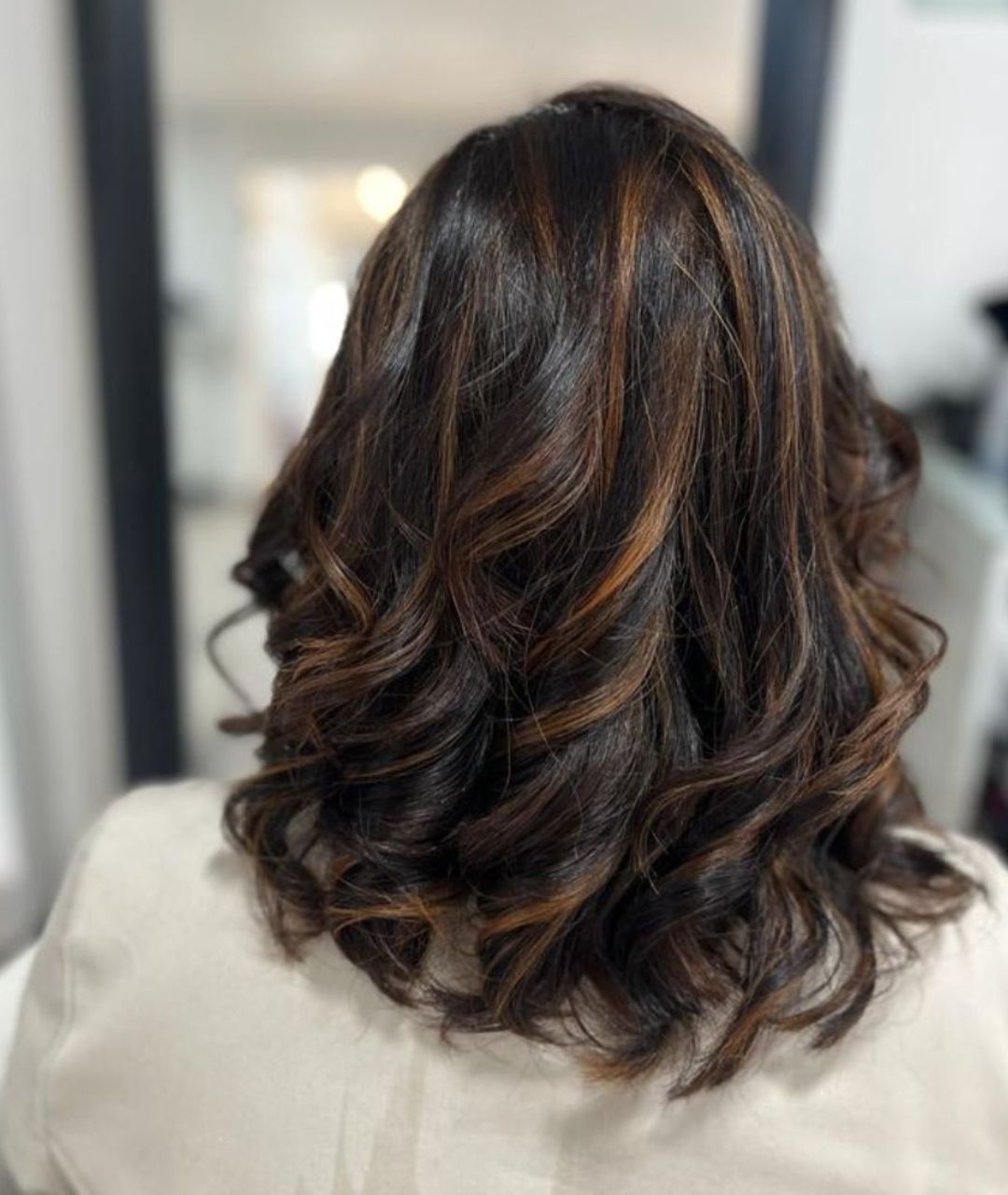 Mèches caramel sur brun brushing bouclé - coiffeur Réunion